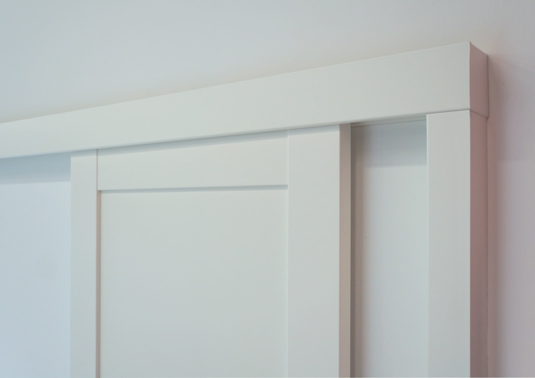 Detail posuvu Klasik pro dřevěné dveře PRÜM (dřevěná garnýž v povrchu Bílá a dřevěné dveřní křídlo model STIL ST Bílá)